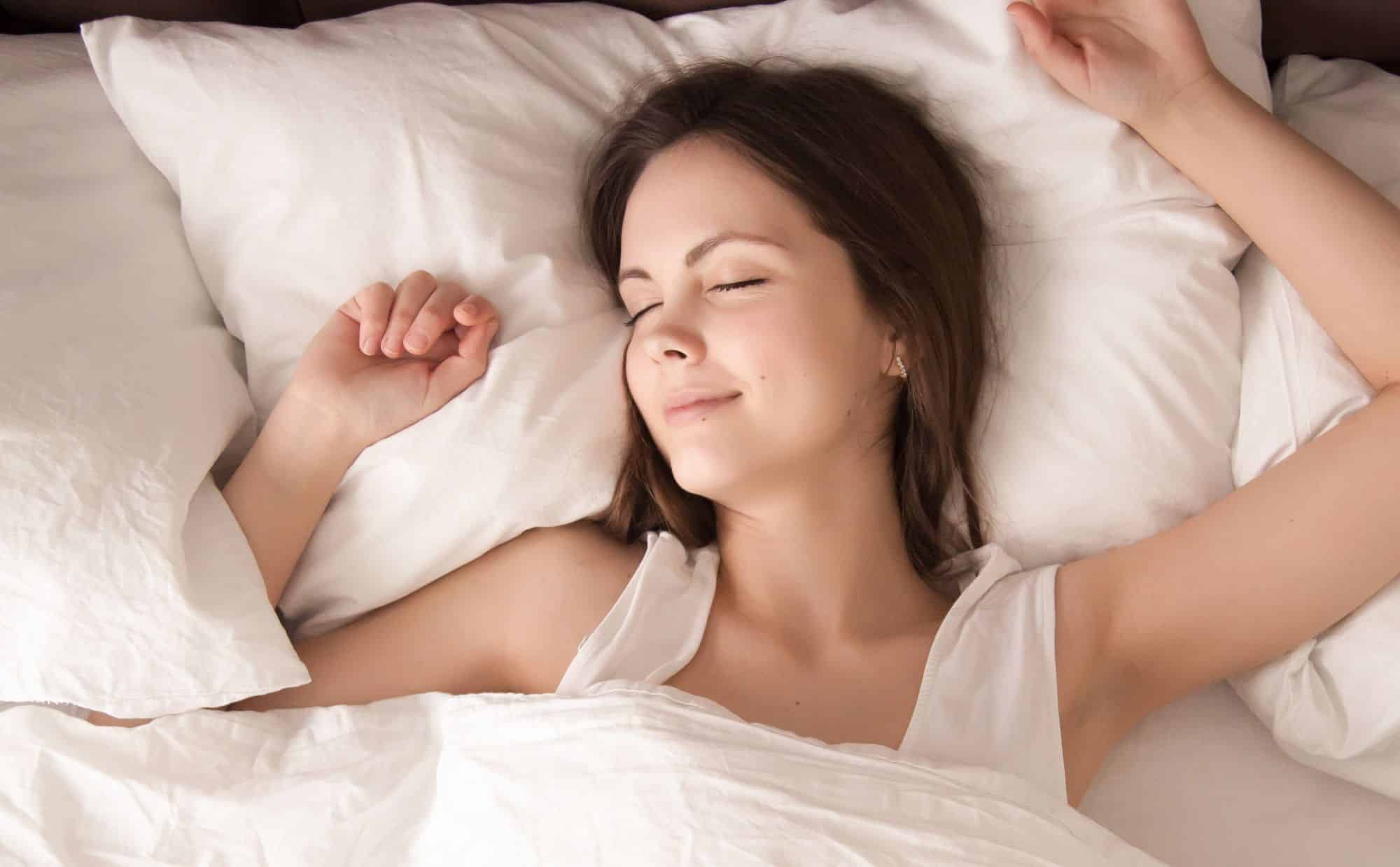 Femme souriante se reposant confortablement sur un matelas blanc, illustrant la qualité du sommeil offerte par les meilleures marques de matelas à Lyon.